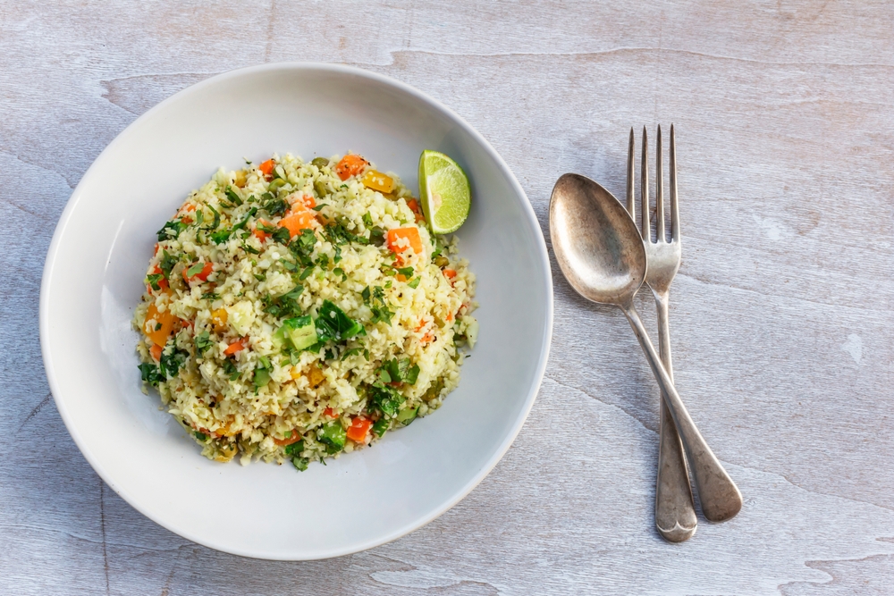 Cauliflower fried rice add carrot bean sweet pepper in white plate on wood background, copy space, top view, good health food concept.