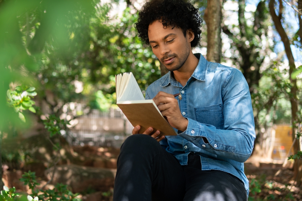 african american man writing in notebook ideas and enjoying nature in the park
