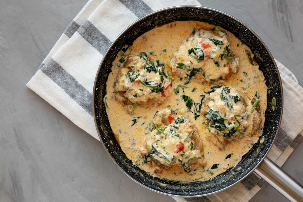 Homemade Creamy Tuscan Chicken with Spinach in a Pan, top view. From above, overhead, flat lay. Copy space.
