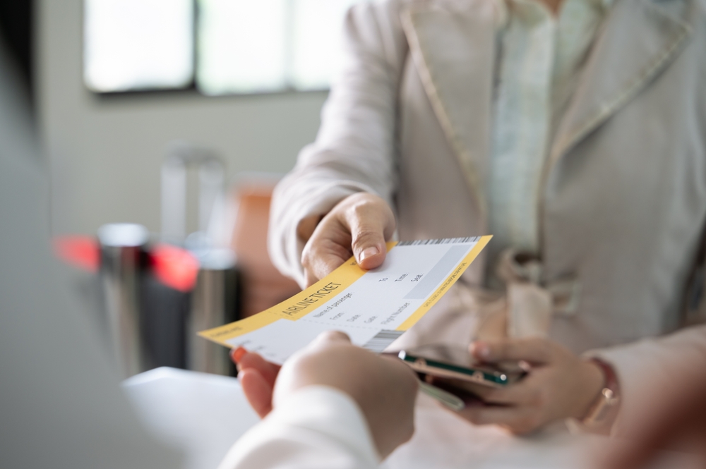 Businesswoman collecting her boarding pass from airlines ground attendant at airport departure gate or check in desk