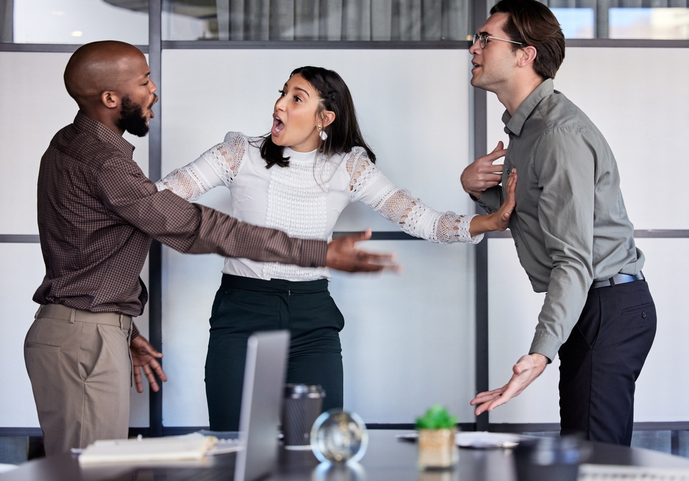 How dare you speak to me like that. Shot of a young businesswoman trying to stop her two colleagues from fighting in an office.