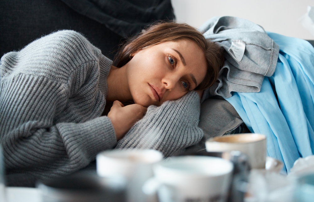 No motivation to do anything. Shot of a depressed young woman lying on her messy couch.