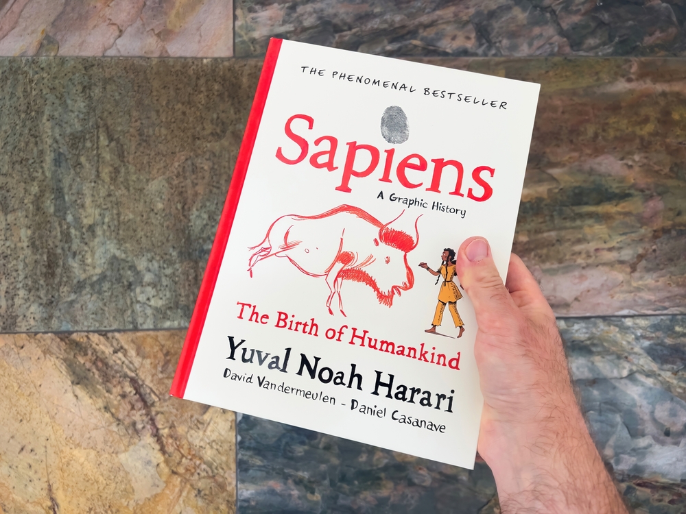 Paris, France - Apr 23, 2023: A male hand holds a book, Sapiens: A Graphic History of Humankind, written by the best-selling author Yuval Noah Harari.