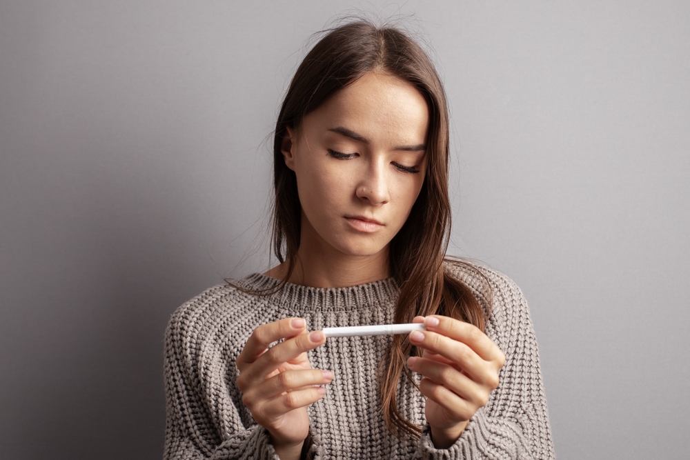 teenager girl looks at a cigarette, stop smoking, tobacco addiction of minors, choice of young people, nicotine refusal