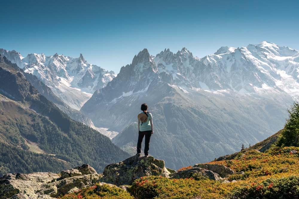 Achievement of female hiker standing with enjoying the Mont Blanc mountain range view during trail in Lac Blanc, French Alps, France