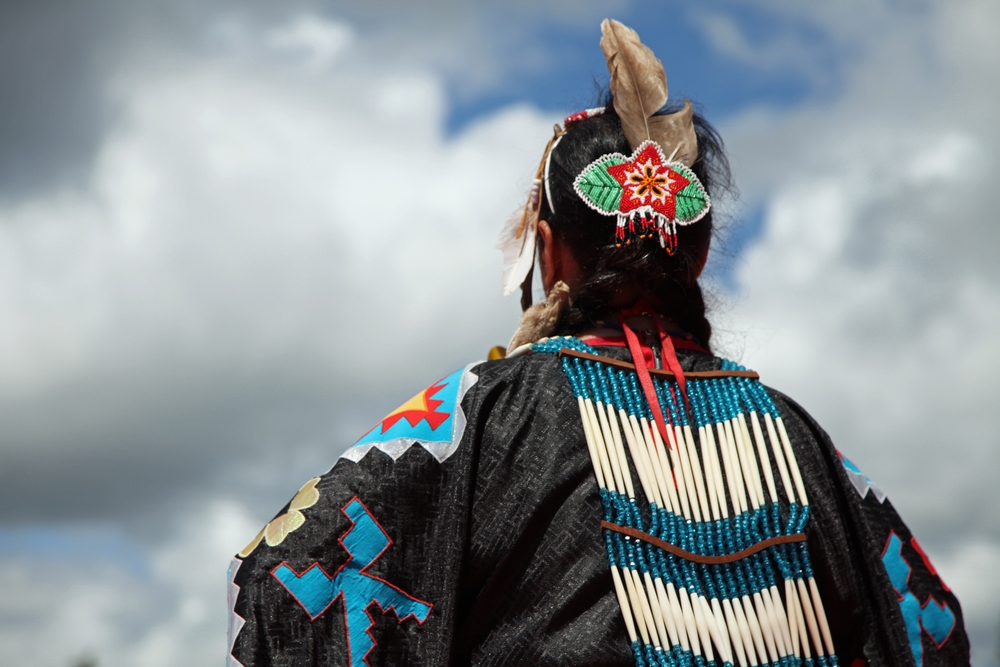 Head of Native American woman in traditional costume against cloudy sky