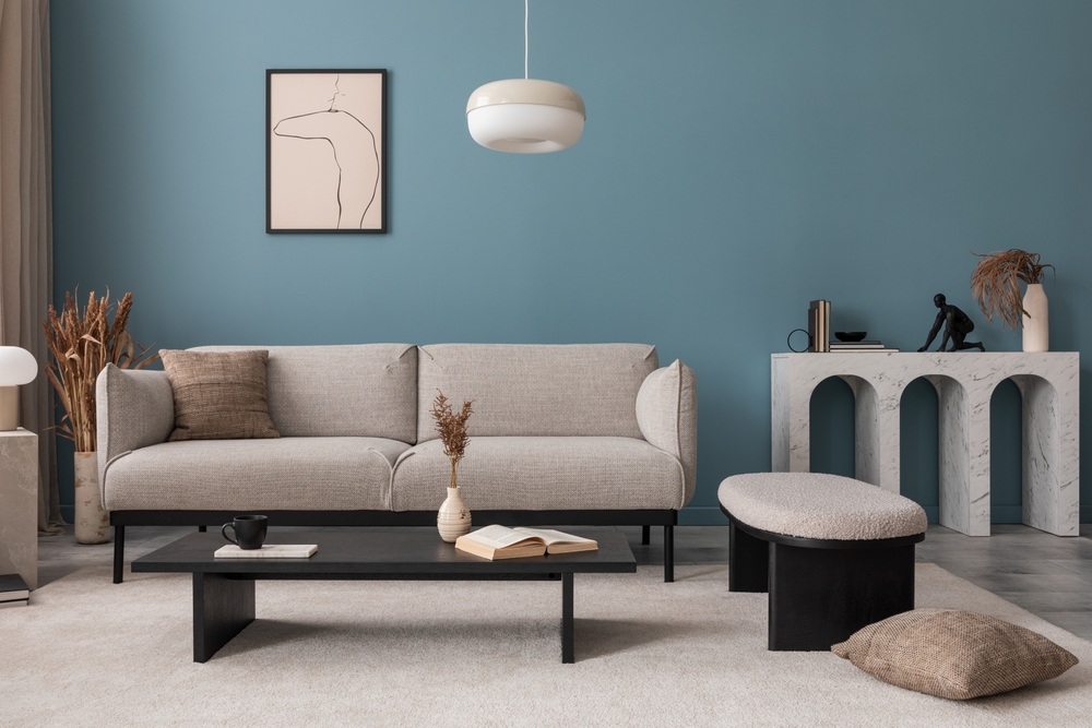 Creative composition of living room interior with mock up poster frame, grey sofa, black coffee table, blue wall, stylish furnitures, decorations and personal accessories. Template. Home decor.
