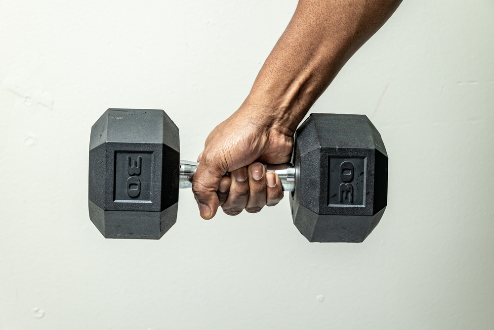 Strong hand gripping a heavy dumbbell isolated on white