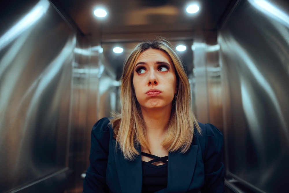 Anxious Office Worker Riding an Elevator at the Workplace. Stressed businesswoman feeling trapped into a broke lift