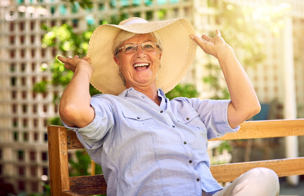 Happy senior woman stretches gracefully in a vibrant outdoor yoga class, surrounded by lush green trees and warm sunlight. Healthy lifestyle concept
