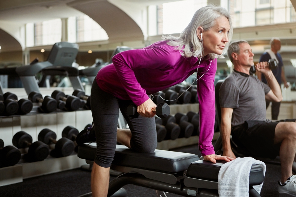 Workout, weights and senior woman in gym for fitness, training and cardio exercise listen to music. Retirement, sports and person with dumbbells for wellness, muscle strength and mobility for health
