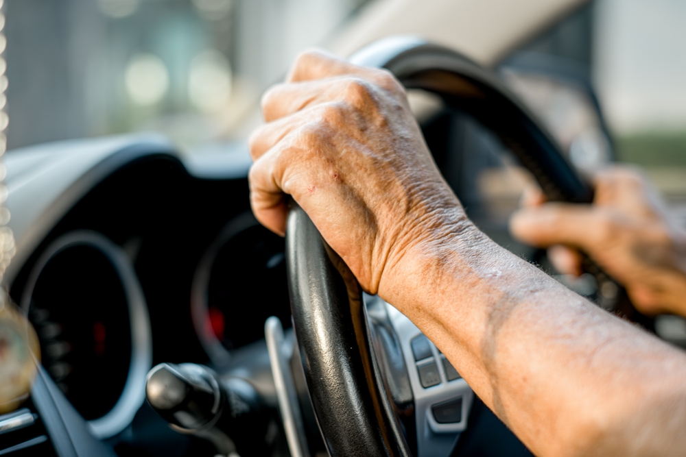 A senior man is driving a car with his hand on the steering wheel. Concept of responsibility and control, as the man is in charge of the vehicle's movement