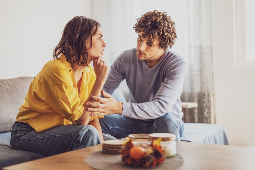Man and woman are sitting at sofa and arguing. Relationship problems.
