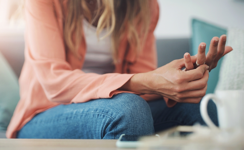 Hands, woman and ring with doubt in marriage for toxic relationship, infidelity or divorce at home. Stress, decision or person on sofa with wedding band, conflict or unhappy for mistake or depression