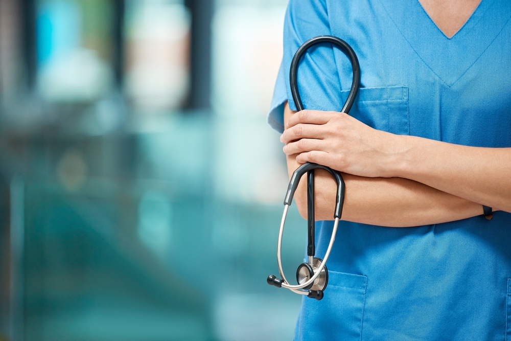 Nurse, woman and arms crossed for cardiology with stethoscope in clinic, support and healthcare. Female person, medical and tool to monitor heart in hospital, medicine and surgeon for treatment