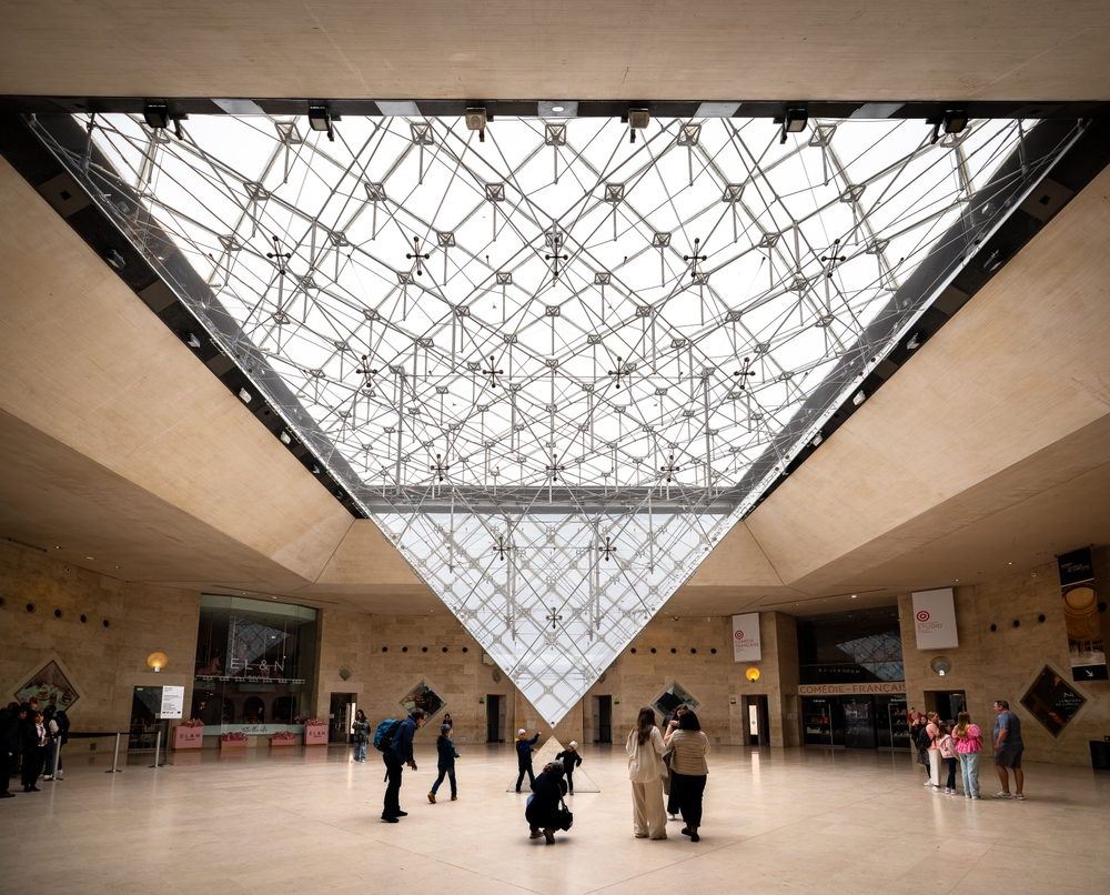 Paris, France - May 8, 2024: People posing in front of the Inverted Pyramid (Pyramide Inversée) located in the Carrousel du Louvre shopping mall in front of the Louvre Museum