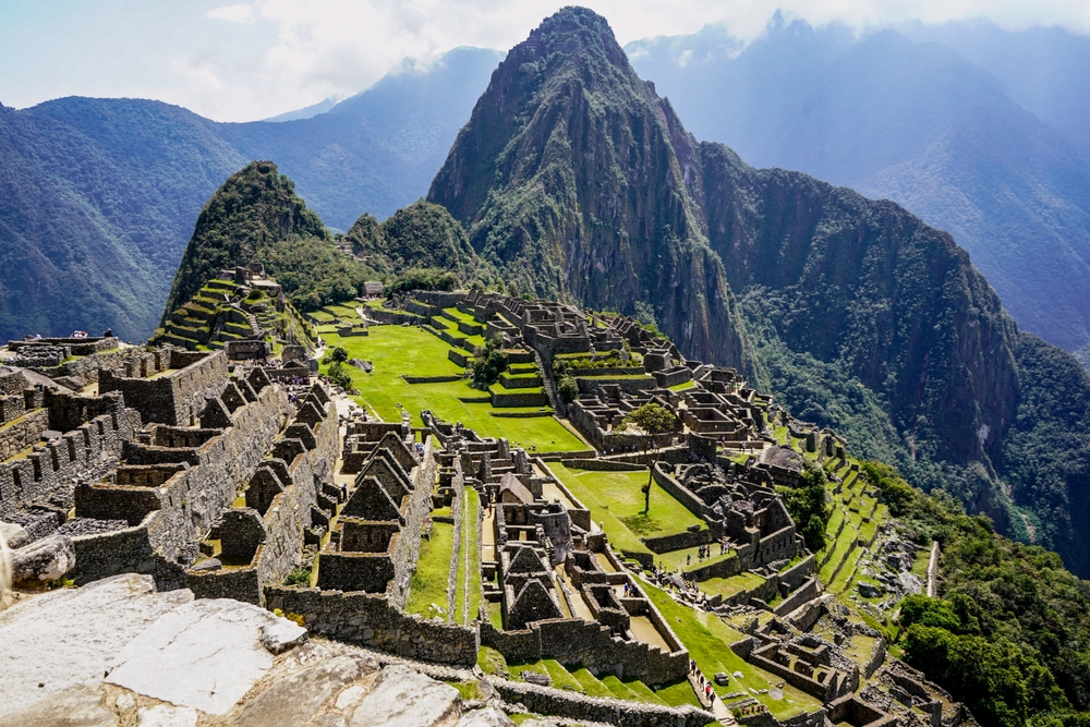 Aerial View of Machu Picchu and Ancient Incan Ruins with Lush Green Mountains and Cloudy Sky in Peru