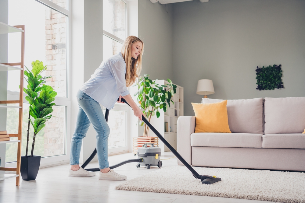 Photo of adorable sweet young lady wear blue shirt vacuum cleaning carpet indoors room home house
