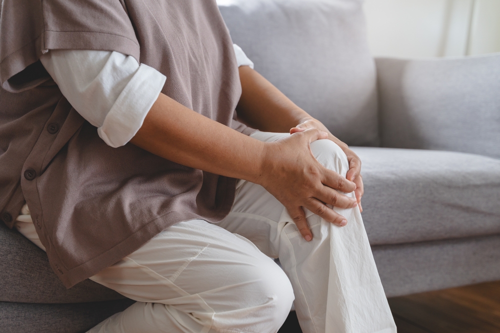 Arthritis is a chronic disease problem in elderly healthcare, Asian old female touching her leg feeling pain in her knee joint, and can't walk properly because of inflammation and pain