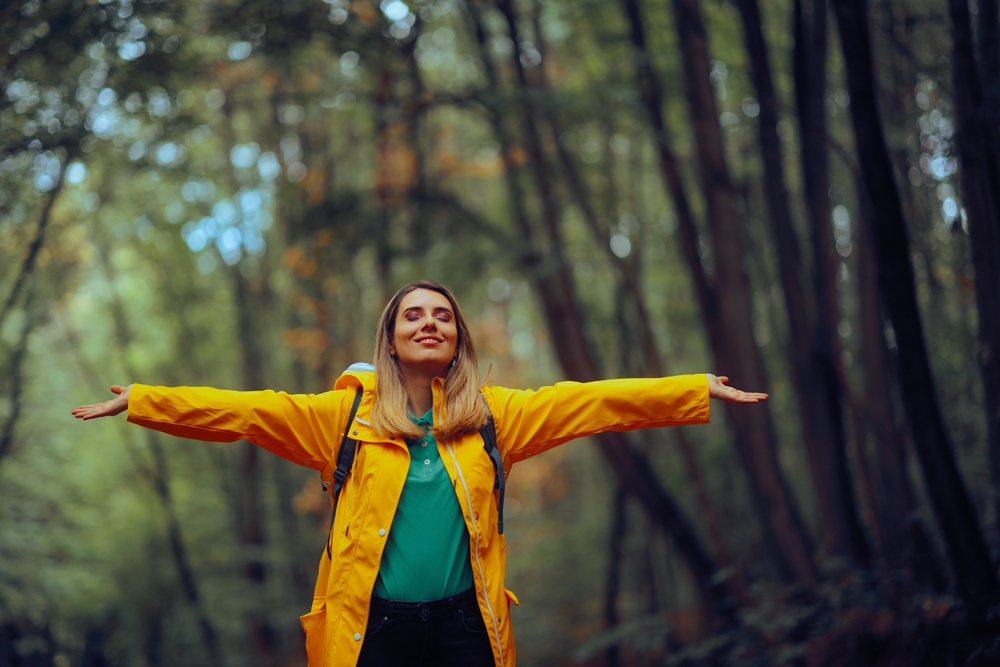 Happy Woman Enjoying the Forest During Spring Season Carefree tourist relaxing outdoors feeling happiness and nature connection