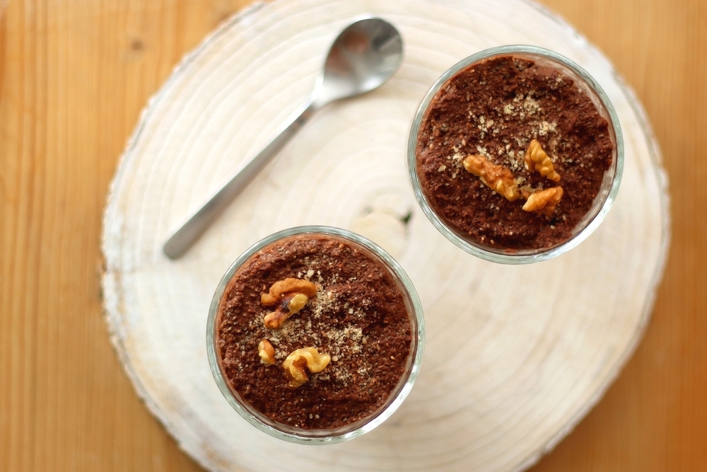 Two bowls of chia seed, chocolate and orange pudding. Healthy snack, wooden background. Top view.
