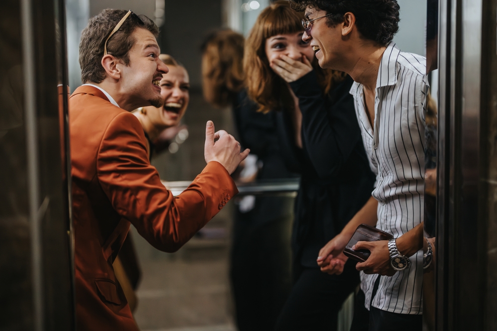 A vibrant group of friends share a joyful moment, laughing together inside an elevator, showcasing connection and happiness.