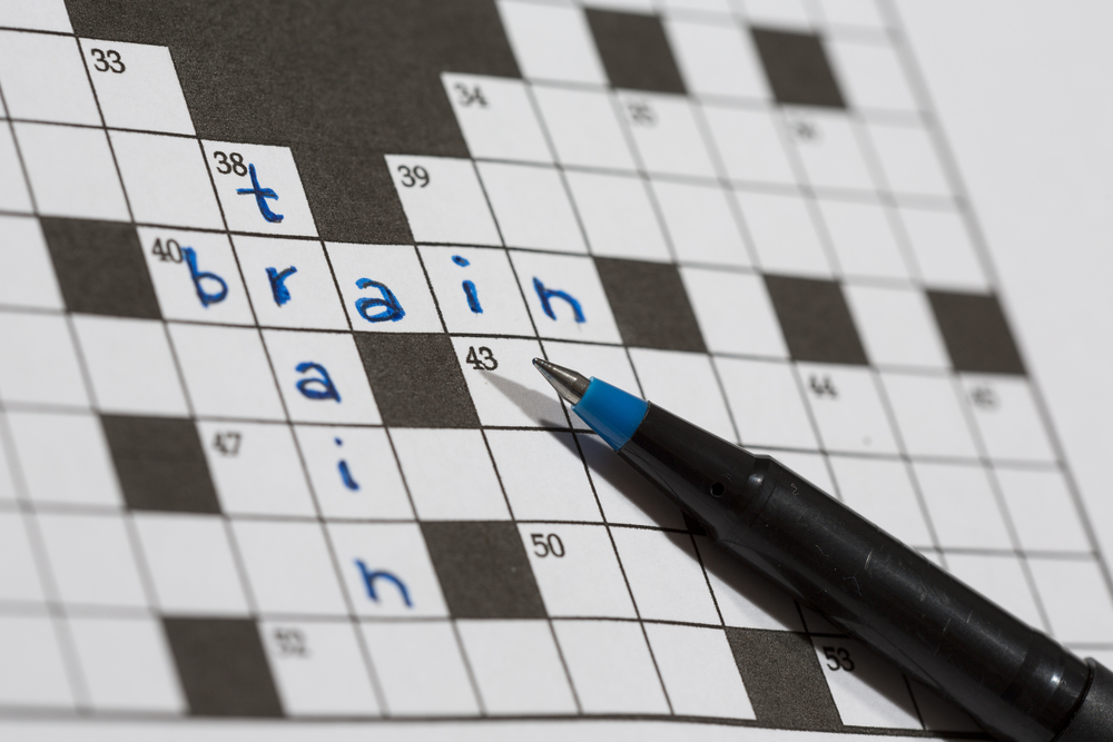 A crossword puzzle saying train and brain. An image of a pencil against an empty crossword puzzle. Crossword puzzles are excellent training for brains.
