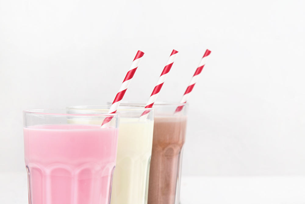 Milkshakes with chocolate, strawberry, banana flavor on a white wooden background
