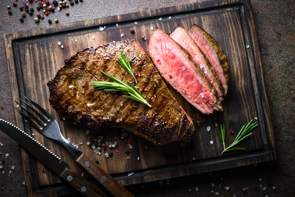 Fresh grilled meat. Grilled beef steak medium rare on wooden cutting board. Top view.