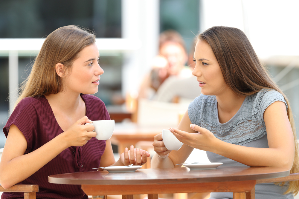 Two serious friends talking sitting in a restaurant