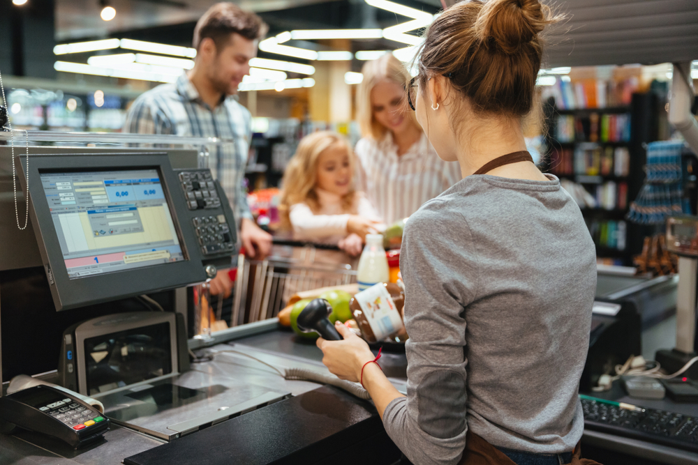 Beautiful family standing at the cash counter buying groceries at the supermarket
