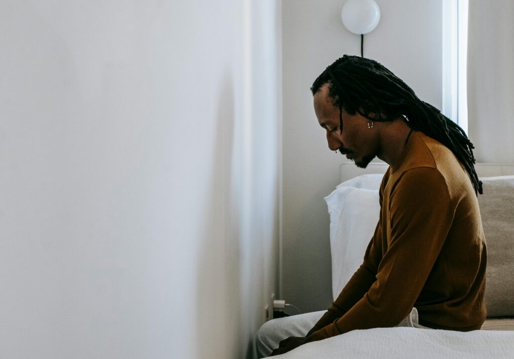 man sitting on edge of bed