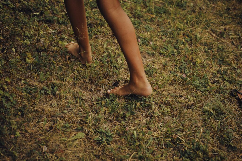 woman walking barefeet on grass