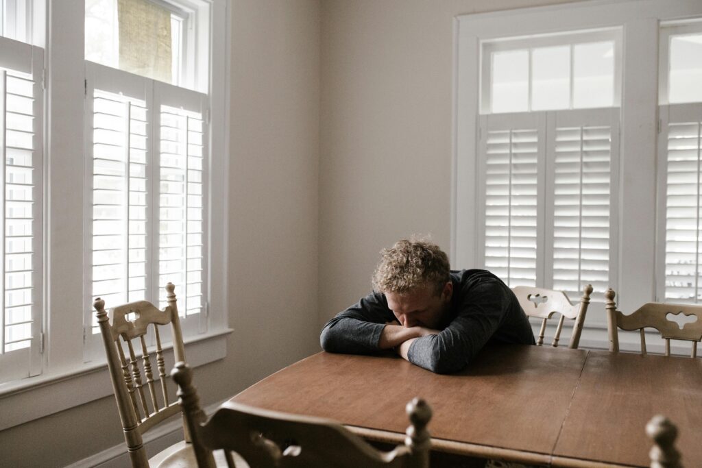 man with head in arms on table