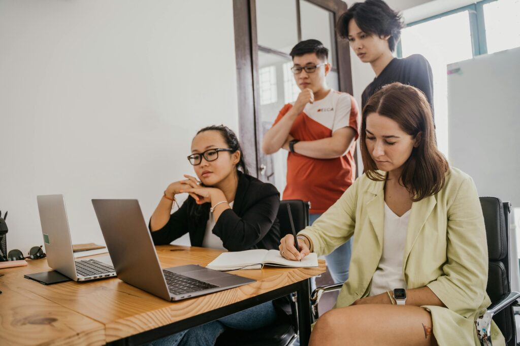 2 woman sitting at desk with laptops