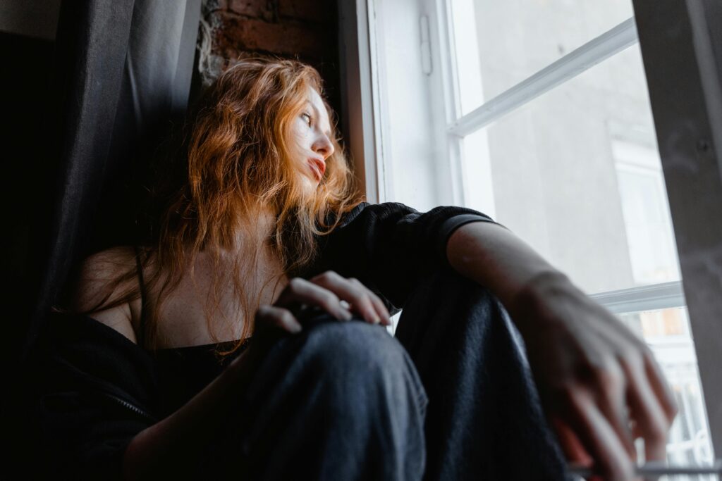 woman with red hair on window sill