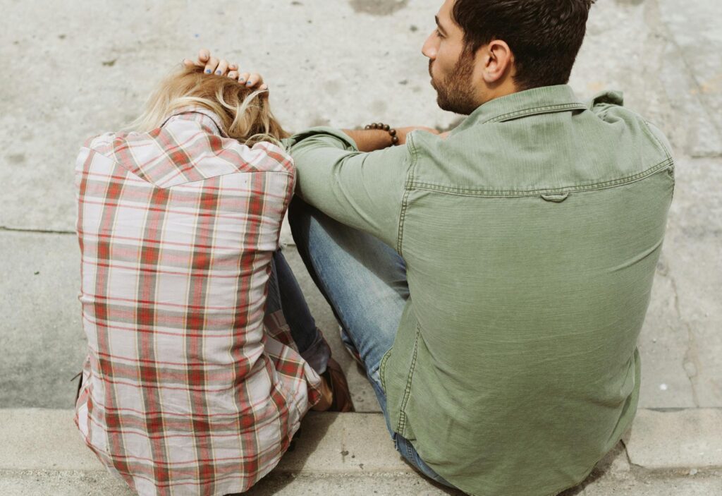 woman and man sitting on curb