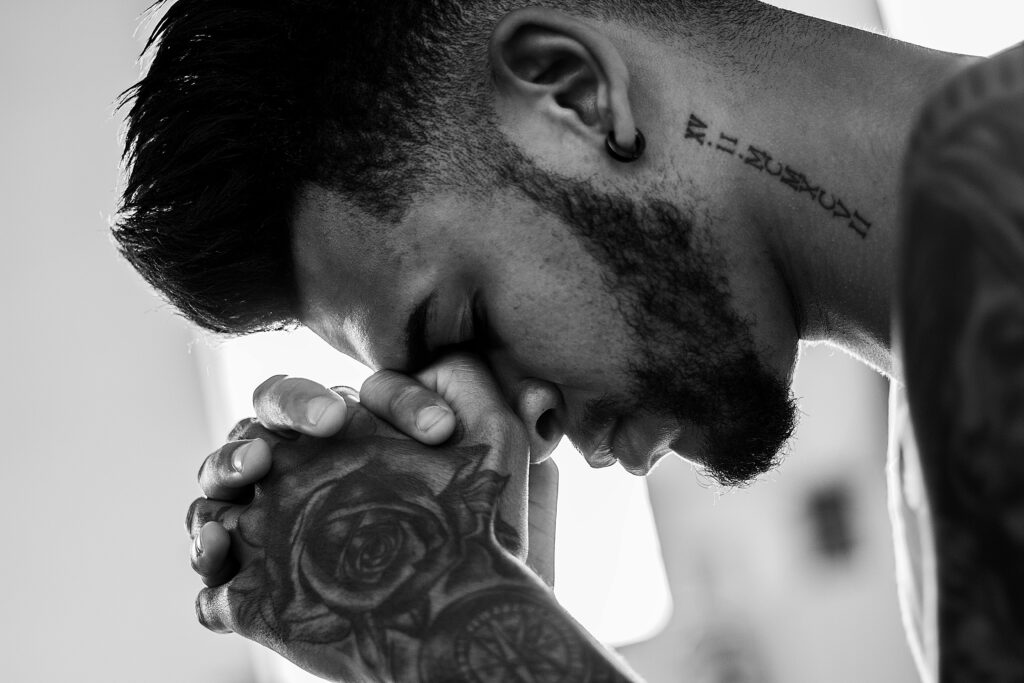 tattooed man with hands on head