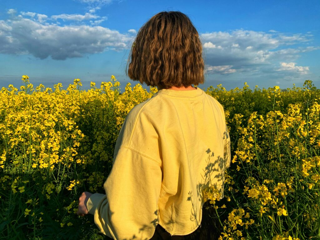 woman with yellow jumper in canola fields