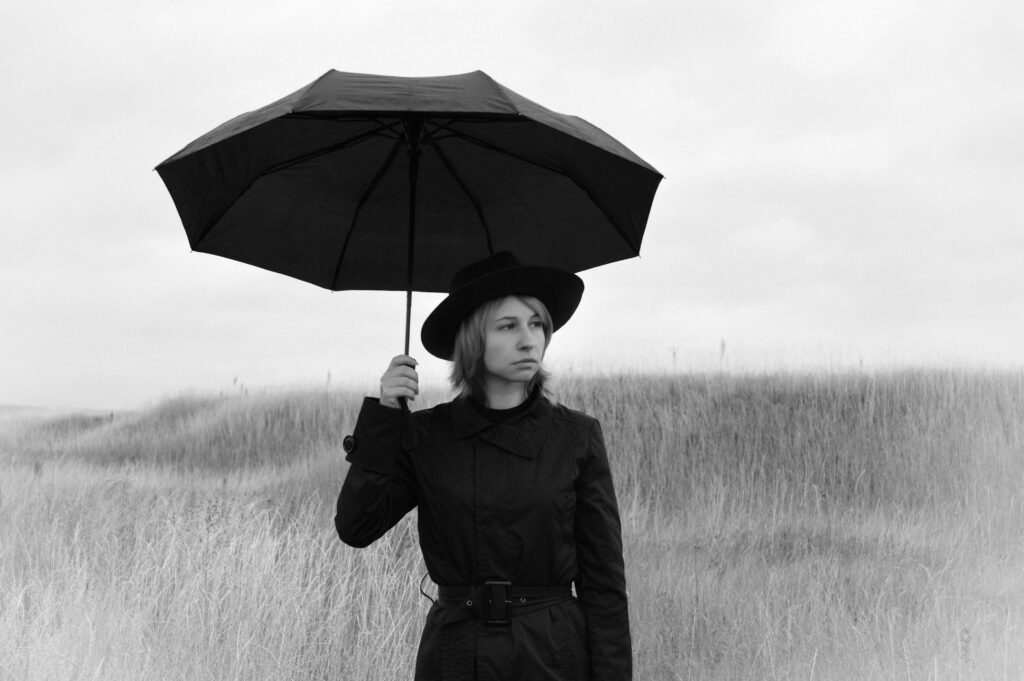 Lonely woman with umbrella in field