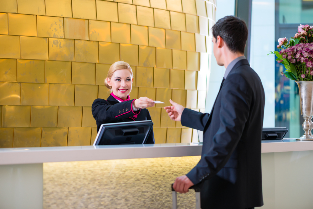 Man in Hotel check in at reception or front office being given key card
