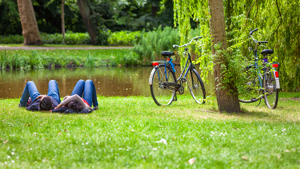 Young couple relaxing on the grass in public park after a bike ride, Vondelpark, Amsterdam, Holland