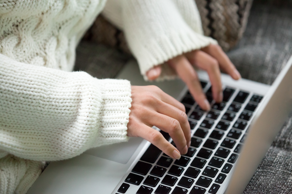Hands of woman typing on keyboard, teen girl working on computer searching online, commenting in social network, using application on laptop, chatting with friend, writing post in blog, close up view