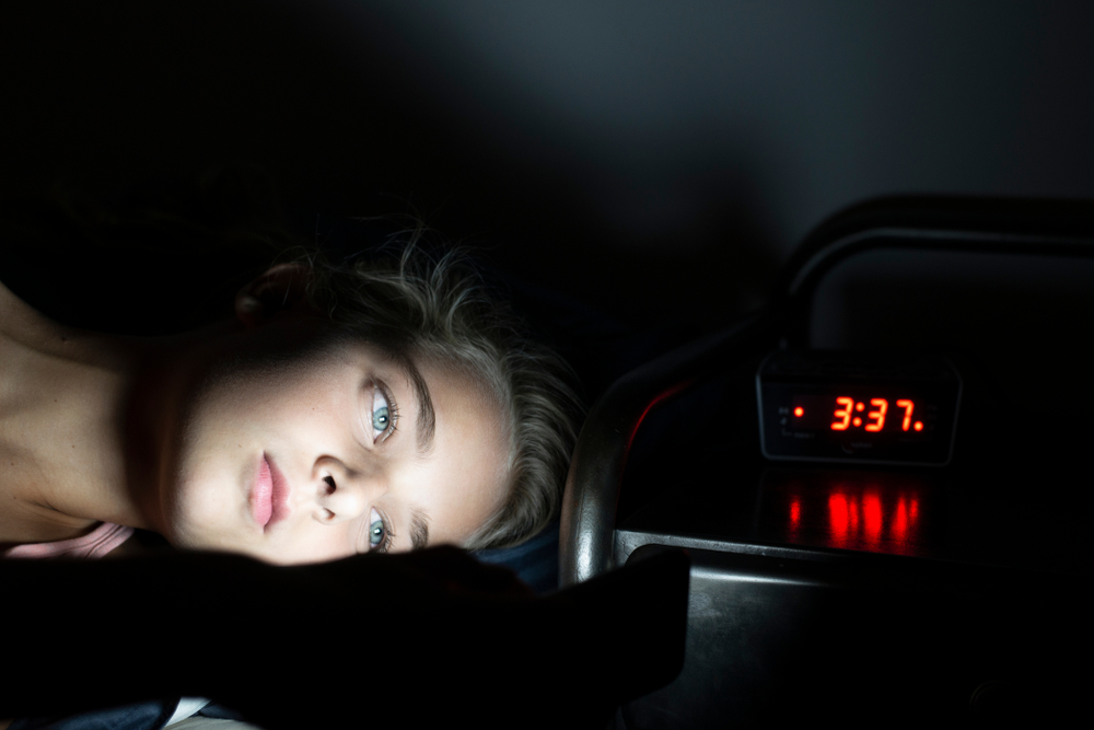 Young girl using smartphone in bed late at night