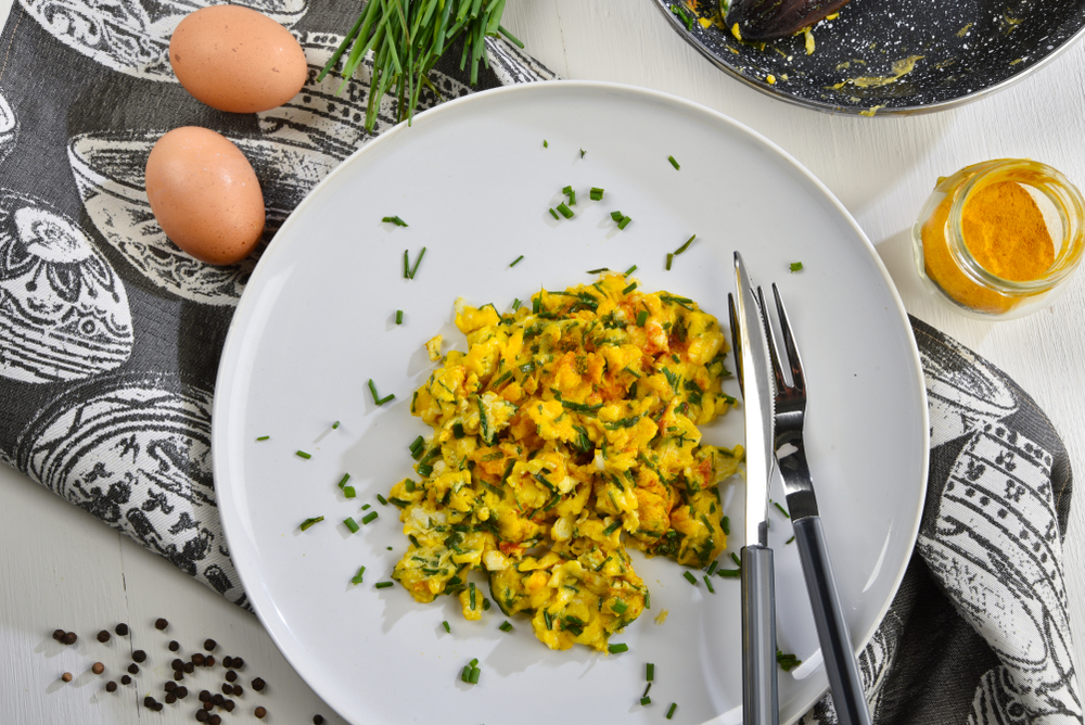 Scrambled eggs in the pan with chives and turmeric