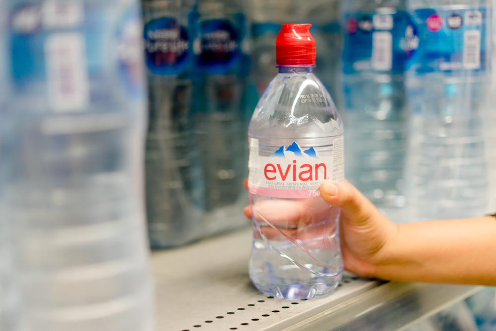 BANGKOK, THAILAND - December 5, 2018 : Woman choosing Evian bottle water beverage on shelves in supermarket store. Evian brand famous drinking water, are placed on shelves in the grocery store.
