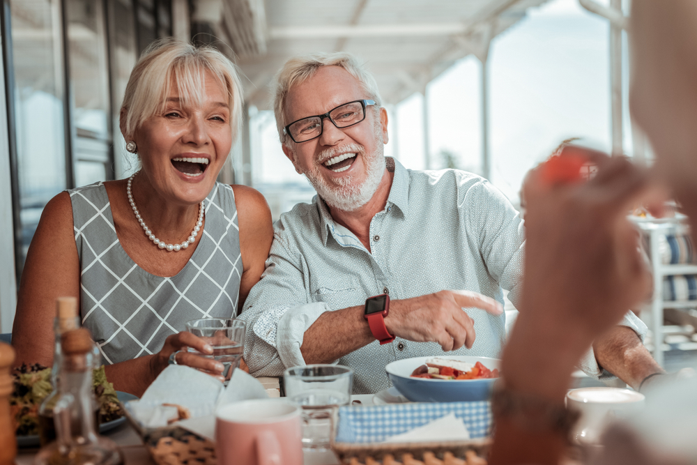 Having fun. Pretty female person sitting close to her partner and going to drink water

