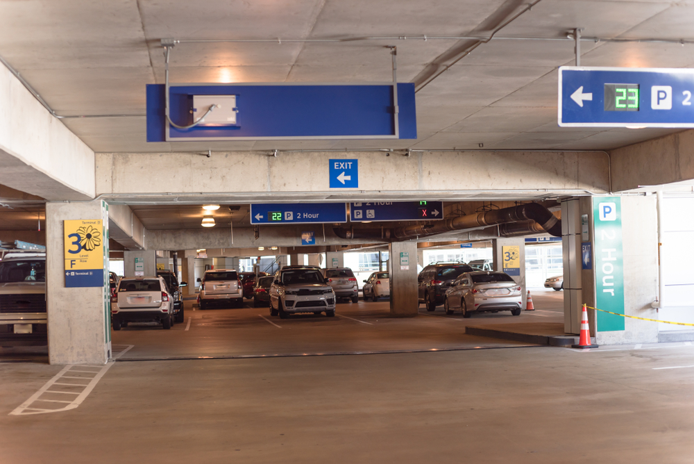 2 hour parking overhead neon sign at indoor airport parking lot displays number of available parking spaces. Available empty spots display counter information
