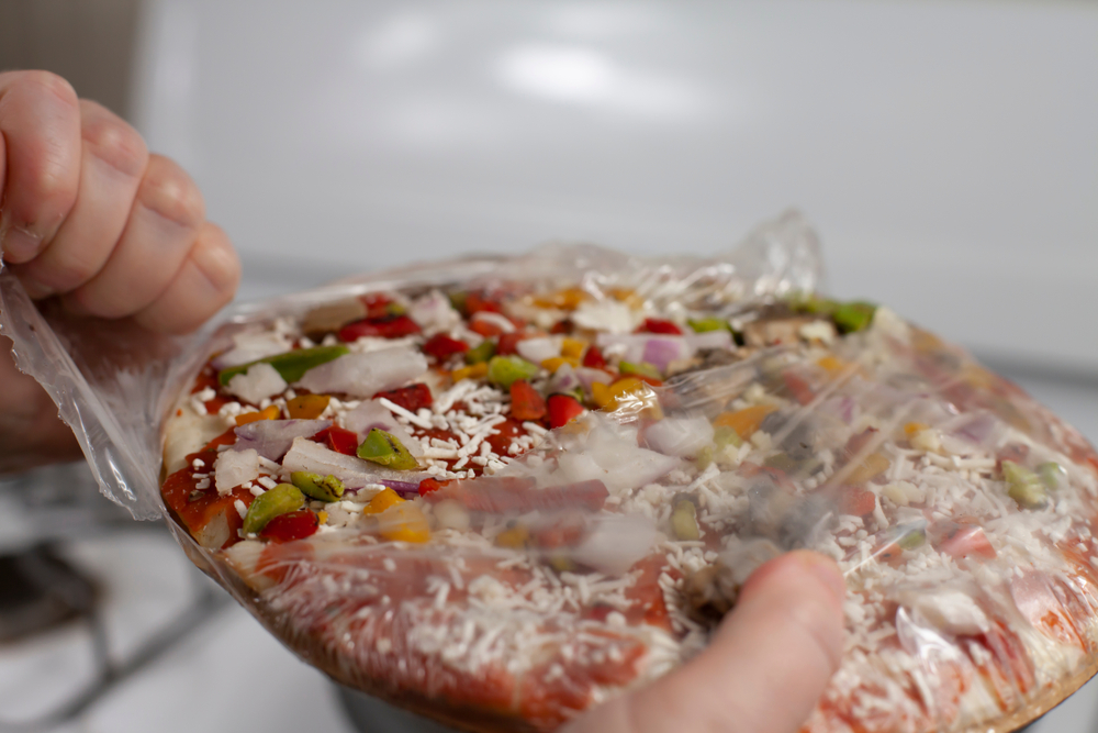 Hand opening a frozen pizza