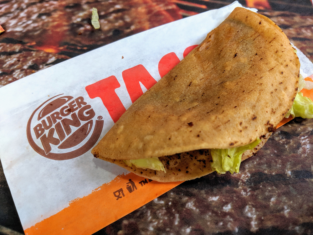 SAN FRANCISCO, CA – JULY 9, 2019: Burger King Crispy Taco and Hamburger. The crispy taco is made with seasoned ground beef, iceberg lettuce, shredded cheddar cheese, and savory taco sauce.